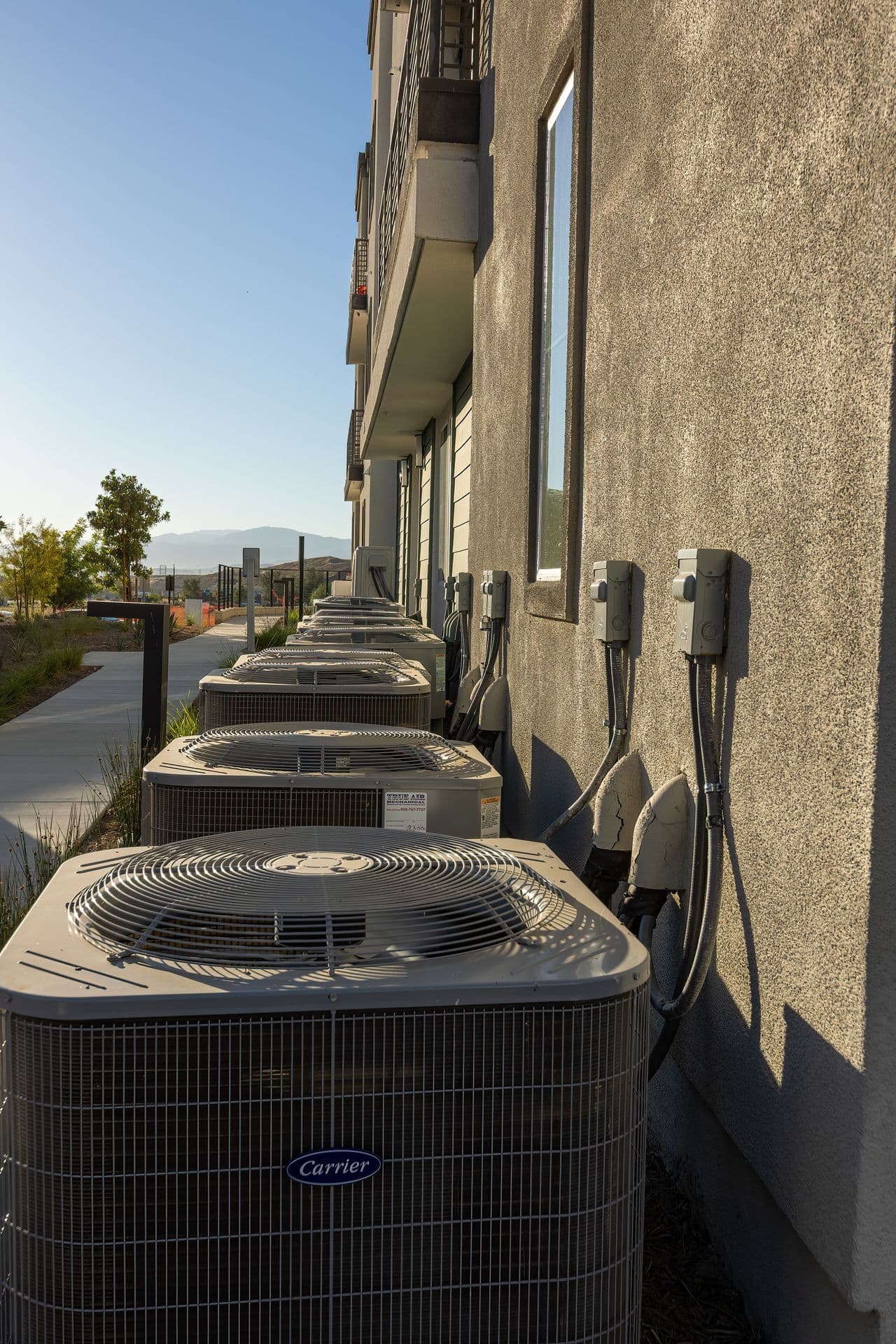 Row of AC condenser units installed along a building